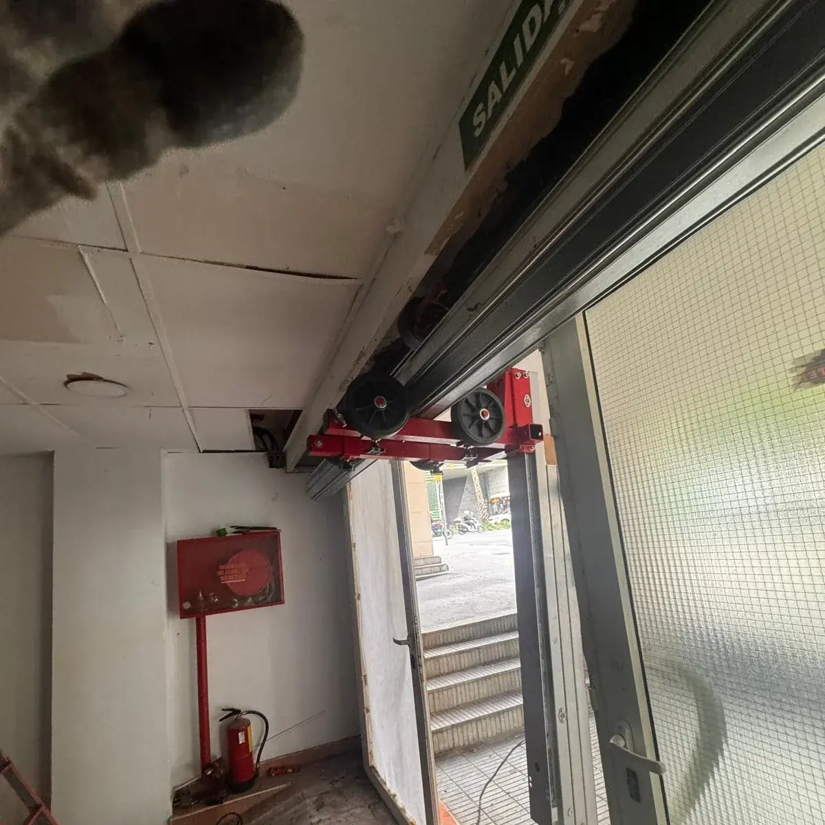 Instalación de la guía superior de una persiana metálica en la entrada de un local