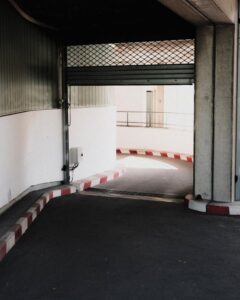 Entrance of an underground parking lot with roller shutter and concrete walls.