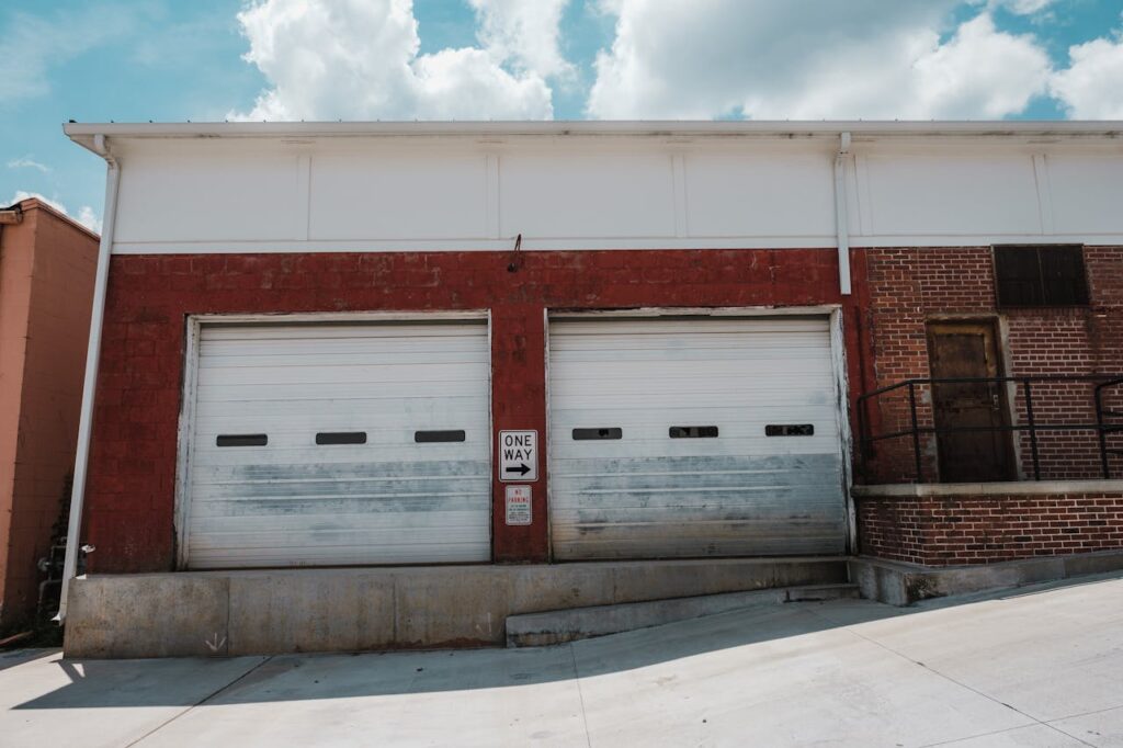 Exterior view of a mixed brick facade with two white roller doors and one-way sign, Buford, GA.