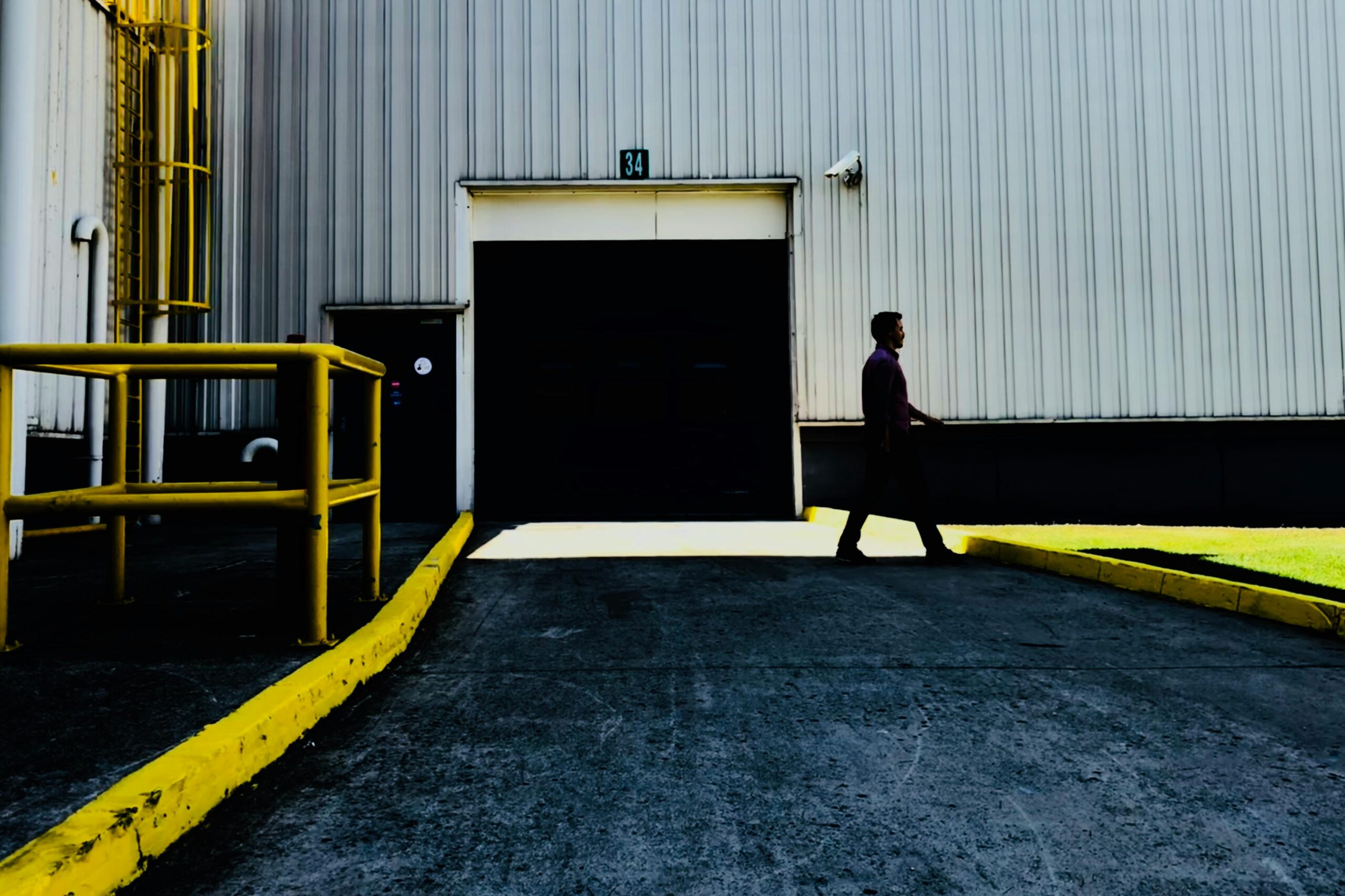 Person walking past a large industrial garage door in a daytime setting.