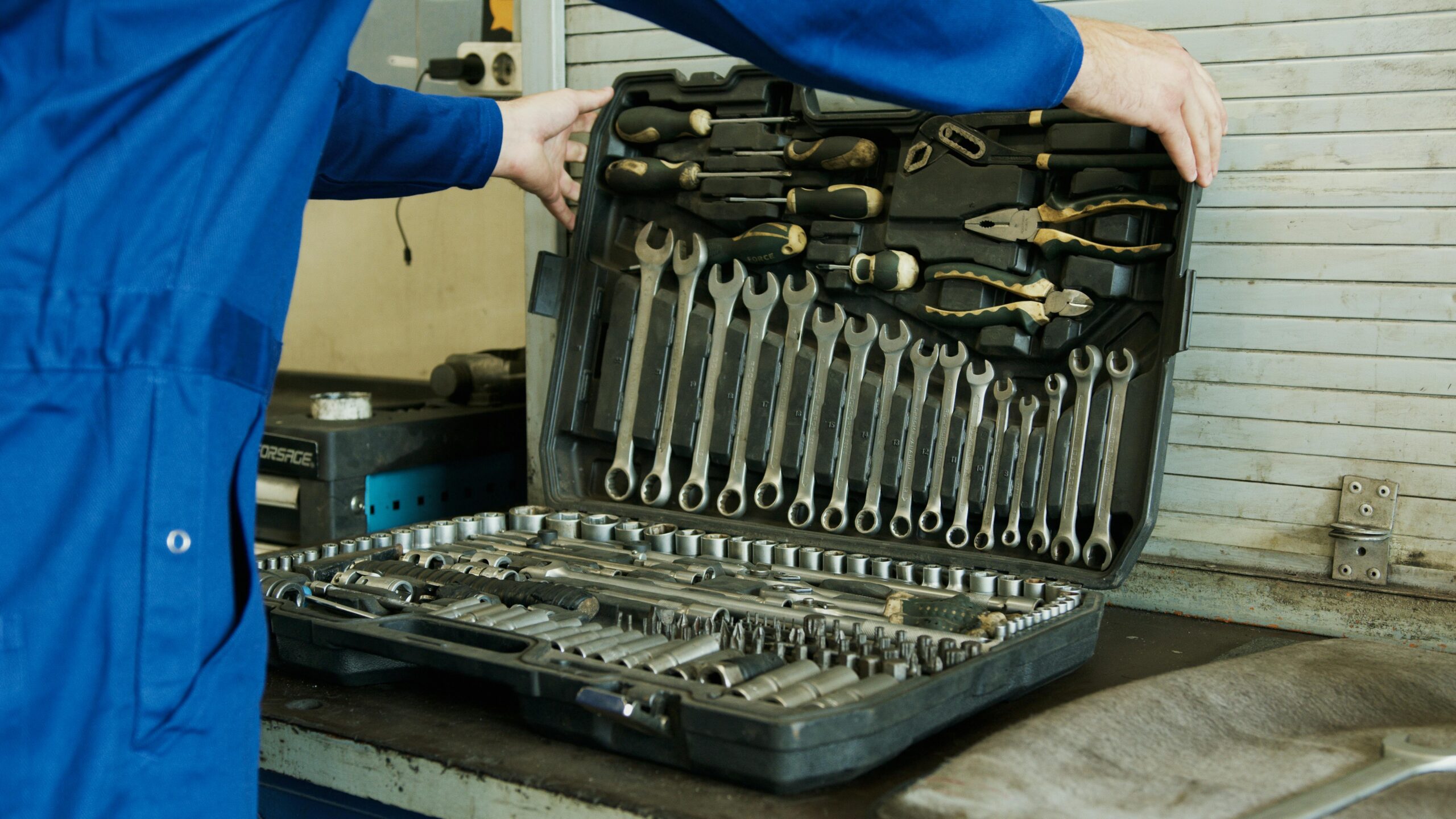 Mantenimiento persianas metálicas en Catalunya Mechanic organizing a comprehensive tool set for vehicle maintenance in a workshop setting.
